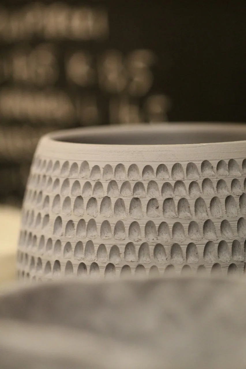 Close view of a textured clay vessel with carved repeating marks.