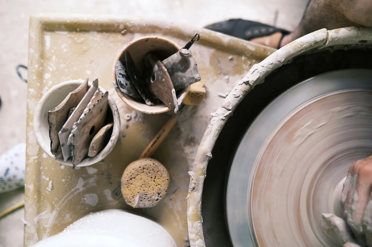 Ceramic tools and clay beside a pottery wheel in a working studio.